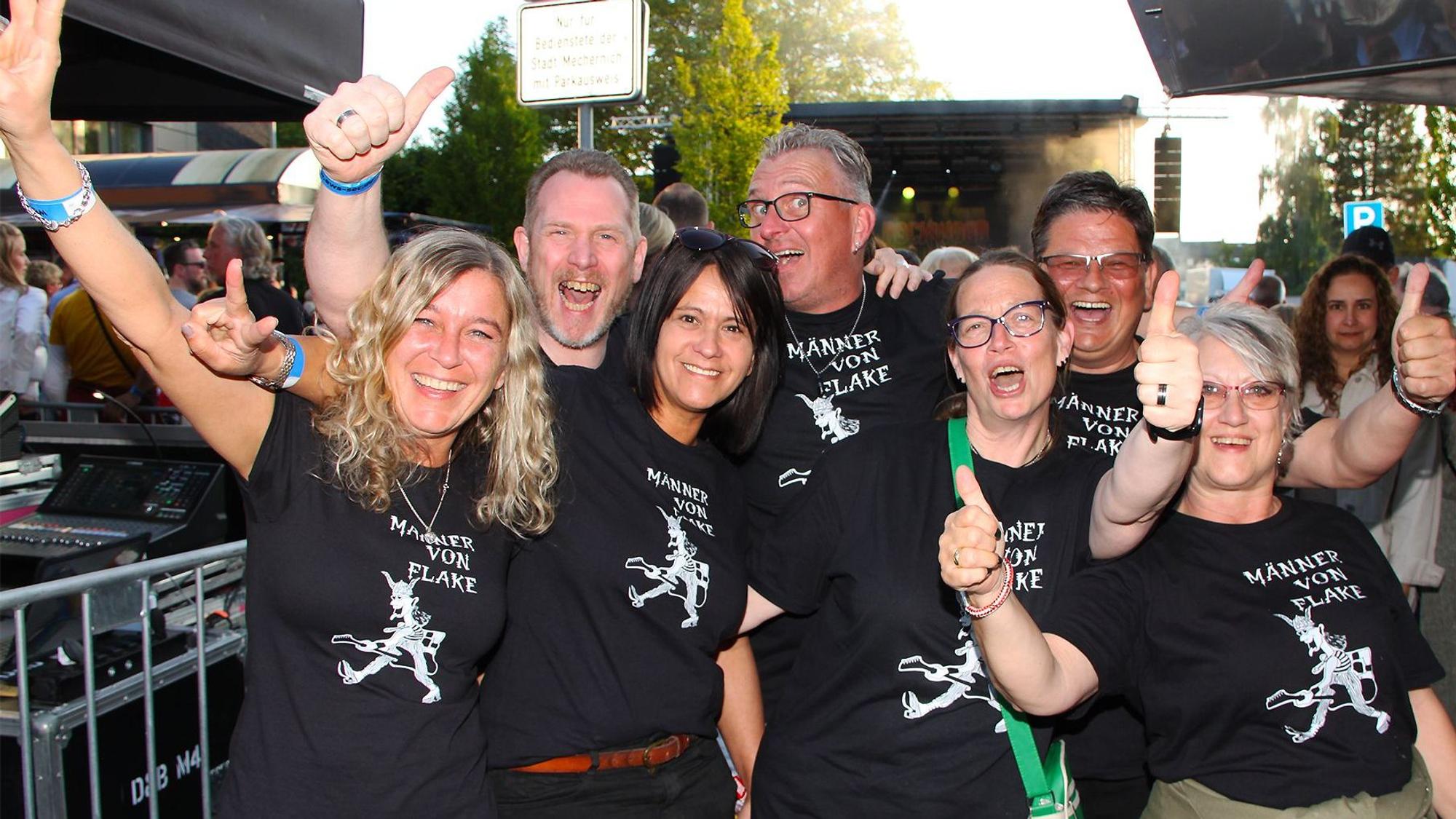 Das Bild zeigt Fans in T-Shirts mit dem Logo der Band „Männer von Flake“.