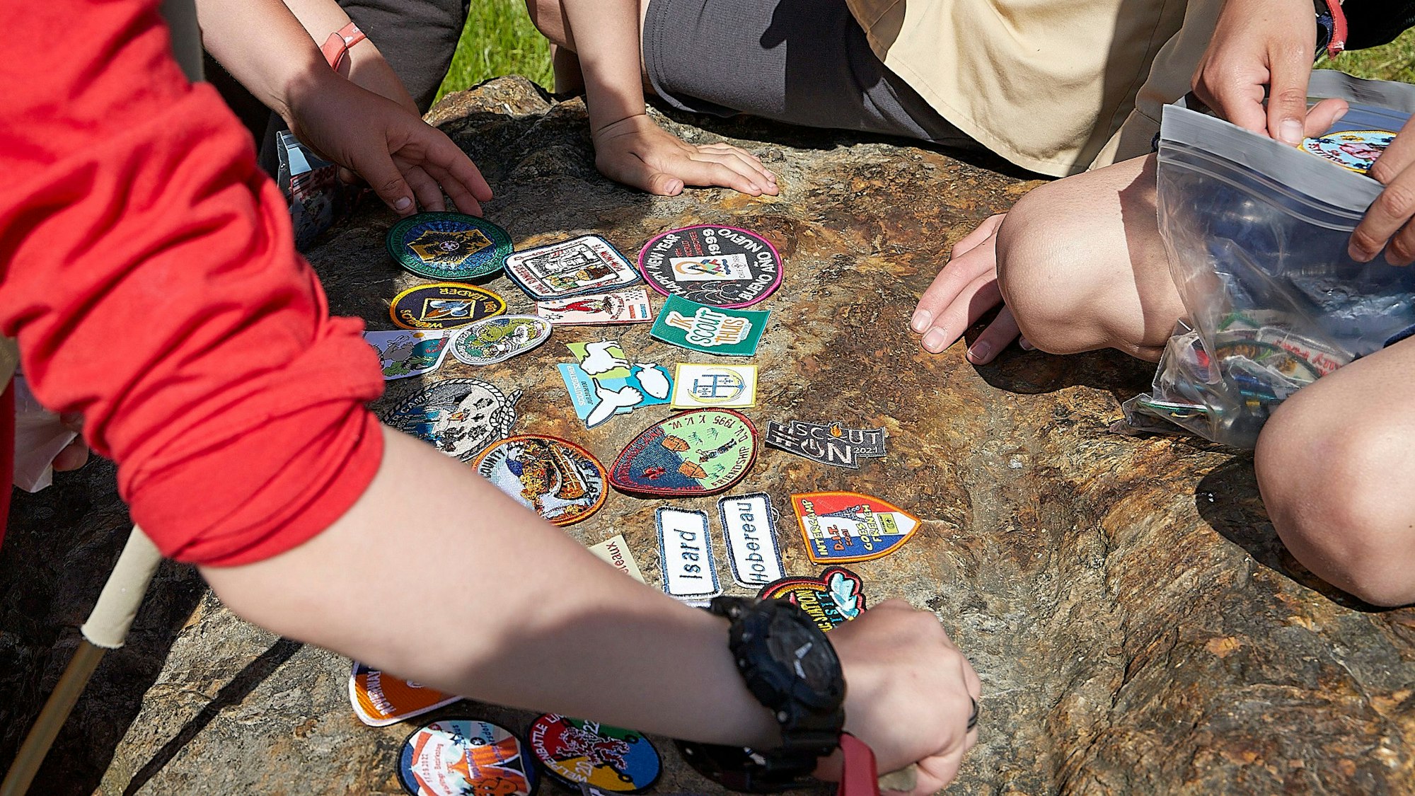 Das Bild zeigt Pfadfinder-Abzeichen, die auf dem Boden ausgelegt sind und getauscht werden.
