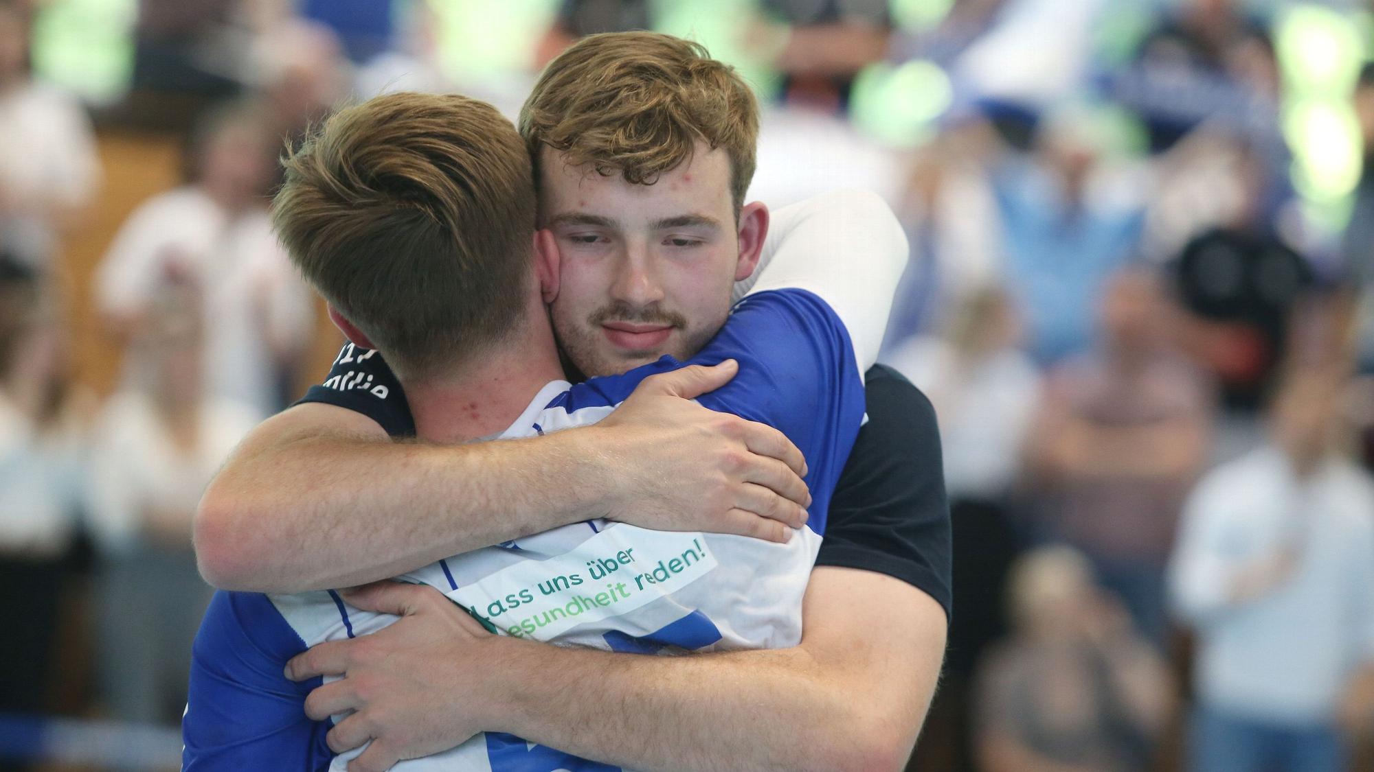 Zwei Handballspieler umarmen sich.