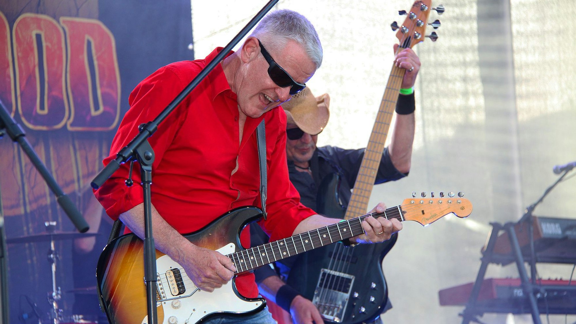 Das Bild zeigt zwei Gitarristen auf einer Bühne.