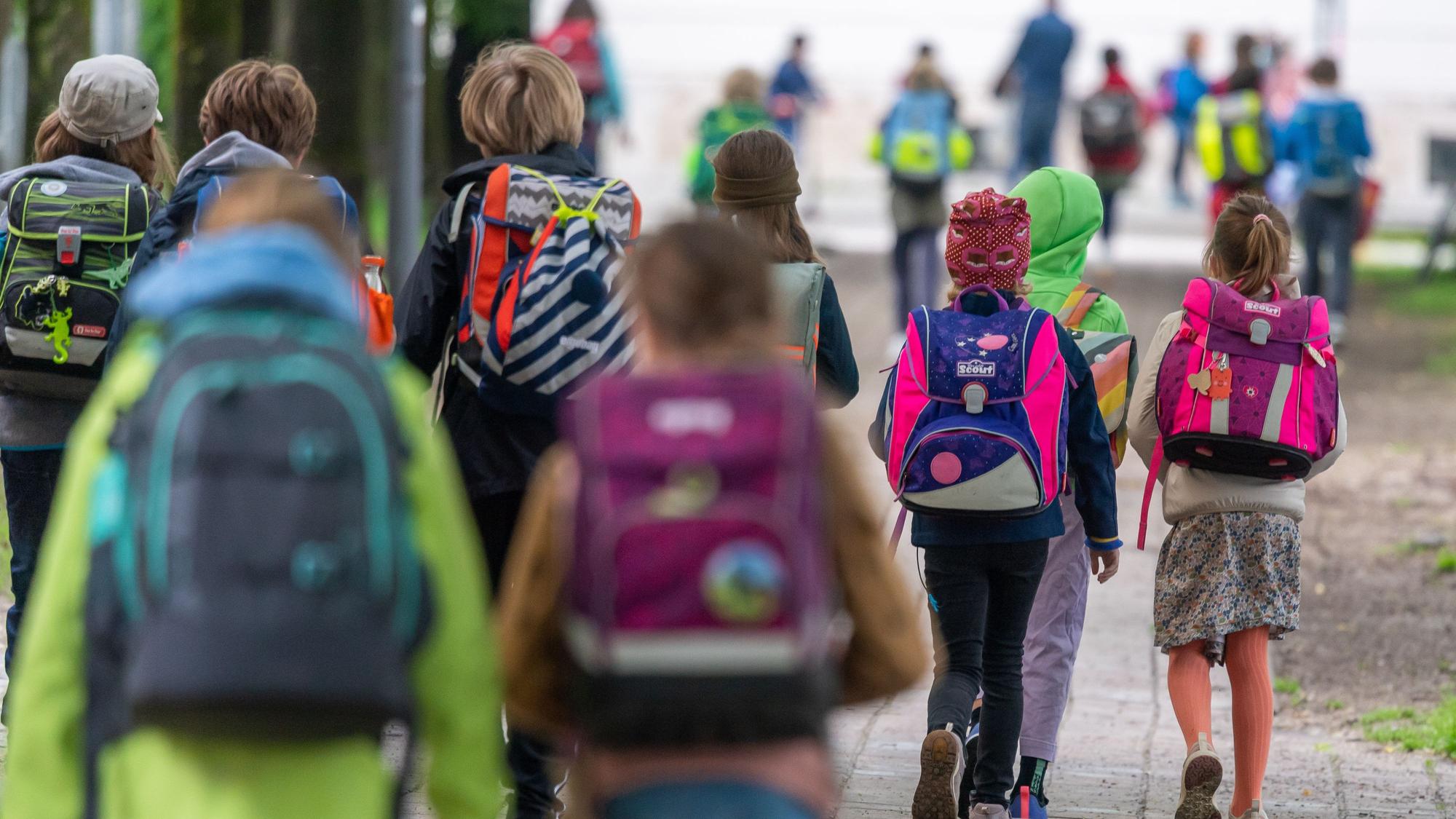 Schulkinder gehen in eine Schule.