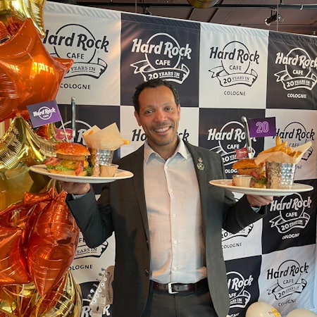 Der Geschäftsführer Uriel Santiago posiert mit Burgern und Pommes.