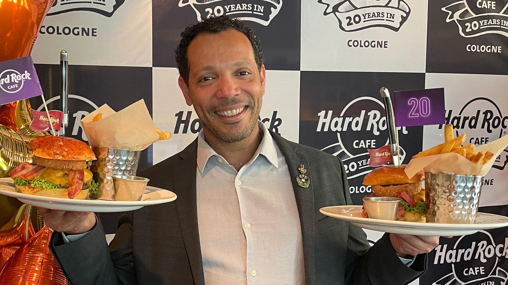 Der Geschäftsführer Uriel Santiago posiert mit Burgern und Pommes.