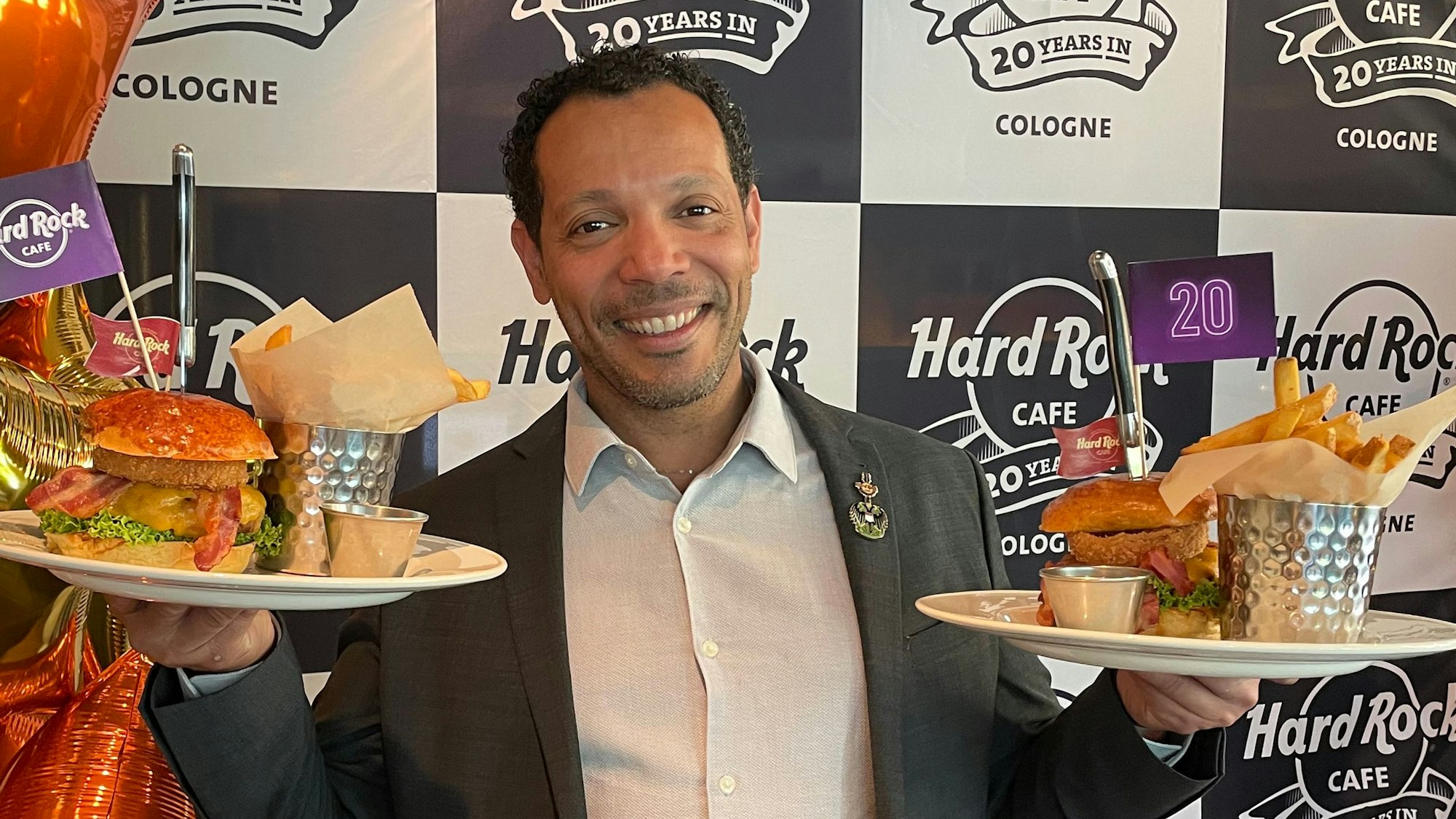 Der Geschäftsführer Uriel Santiago posiert mit Burgern und Pommes.