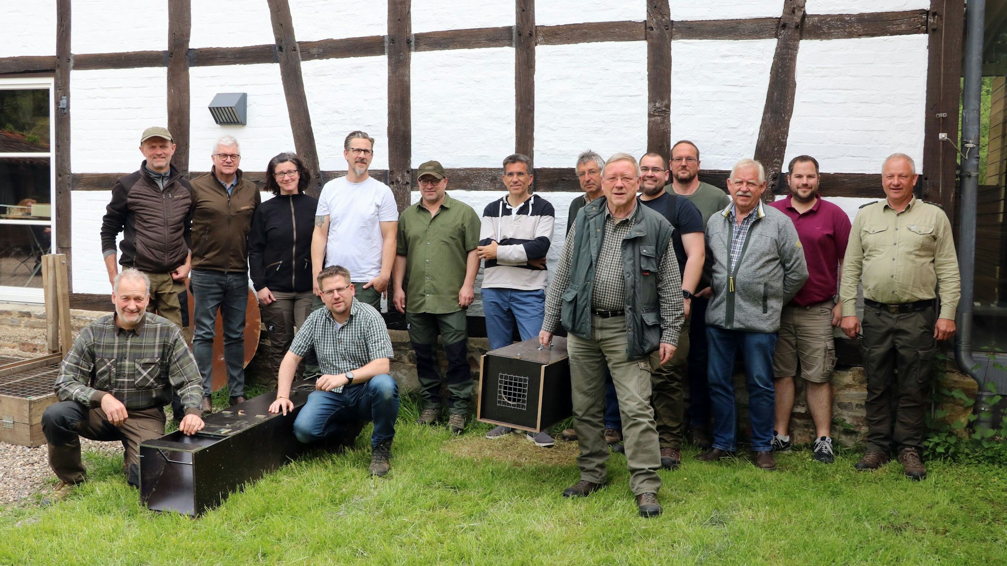 Menschen stehen mit Lebendfallen vor einem Fachwerkgebäude.