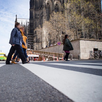 Zwei Menschen queren einen Zebrastreifen nahe des Domes.