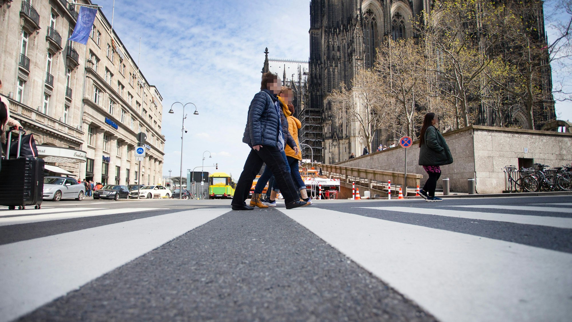 Zwei Menschen queren einen Zebrastreifen nahe des Domes.