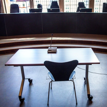 Tisch und Stuhl für Zeugenaussagen stehen vor einem Fenster. Auf dem Tisch ein Mikro.