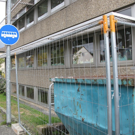 Die Kita in Hennef befindet sich hinter einem Bauzaun. Vor dem Zaun steht ein Schild, das darauf hinweist, dass hier nur Busse langfahren dürfen.