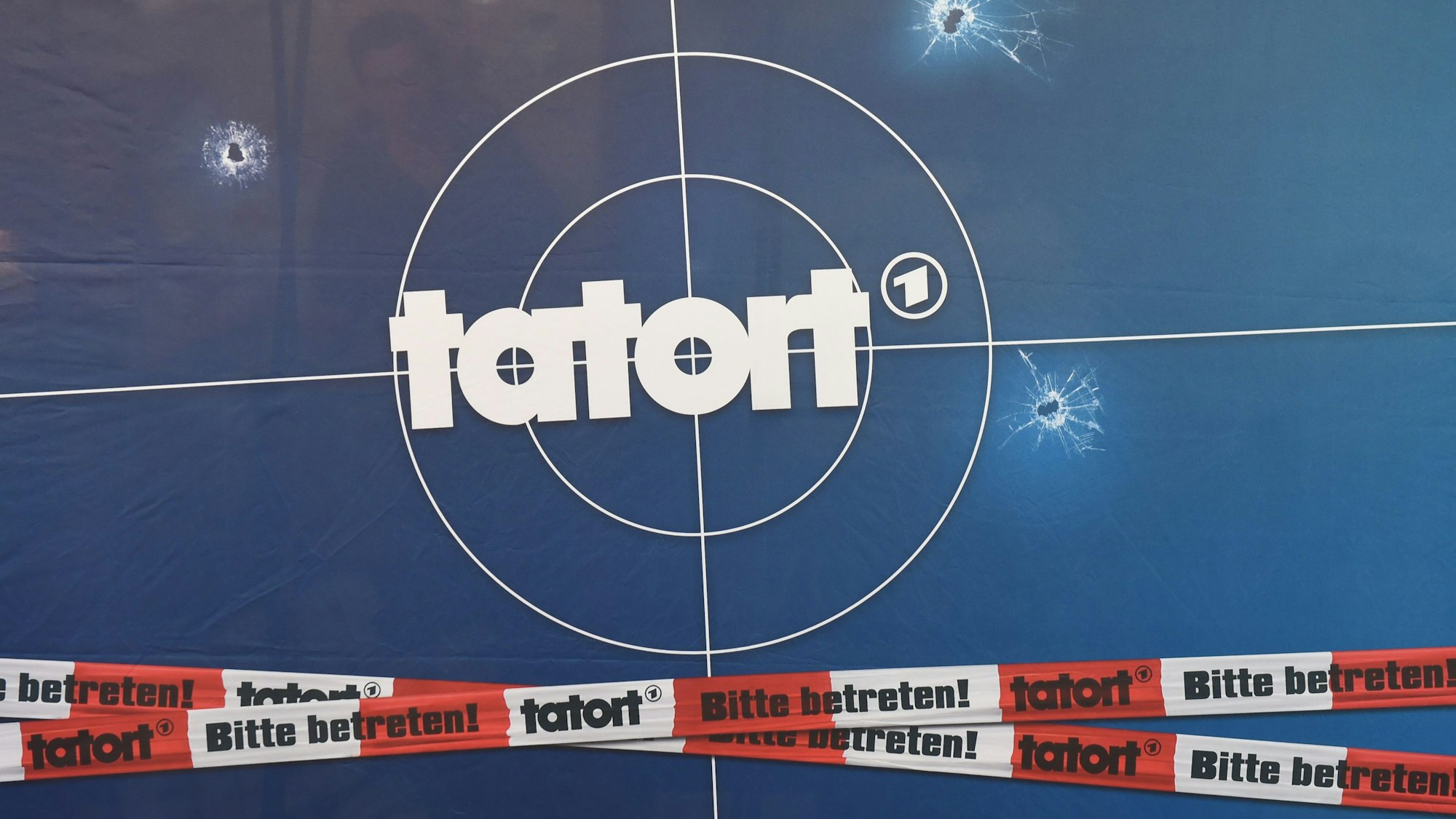 ARCHIV - 14.03.2016, Bayern, München: Auf einer Fotorückwand sind das Logo der Fernsehreihe «Tatort», Einschusslöcher und Absperrband abgebildet, aufgenommen bei der Premiere des Jubiläums-«Tatorts». (zu dpa «Tatort»-Zuschauerzahl schrumpft deutlich») Foto: Tobias Hase/dpa +++ dpa-Bildfunk +++