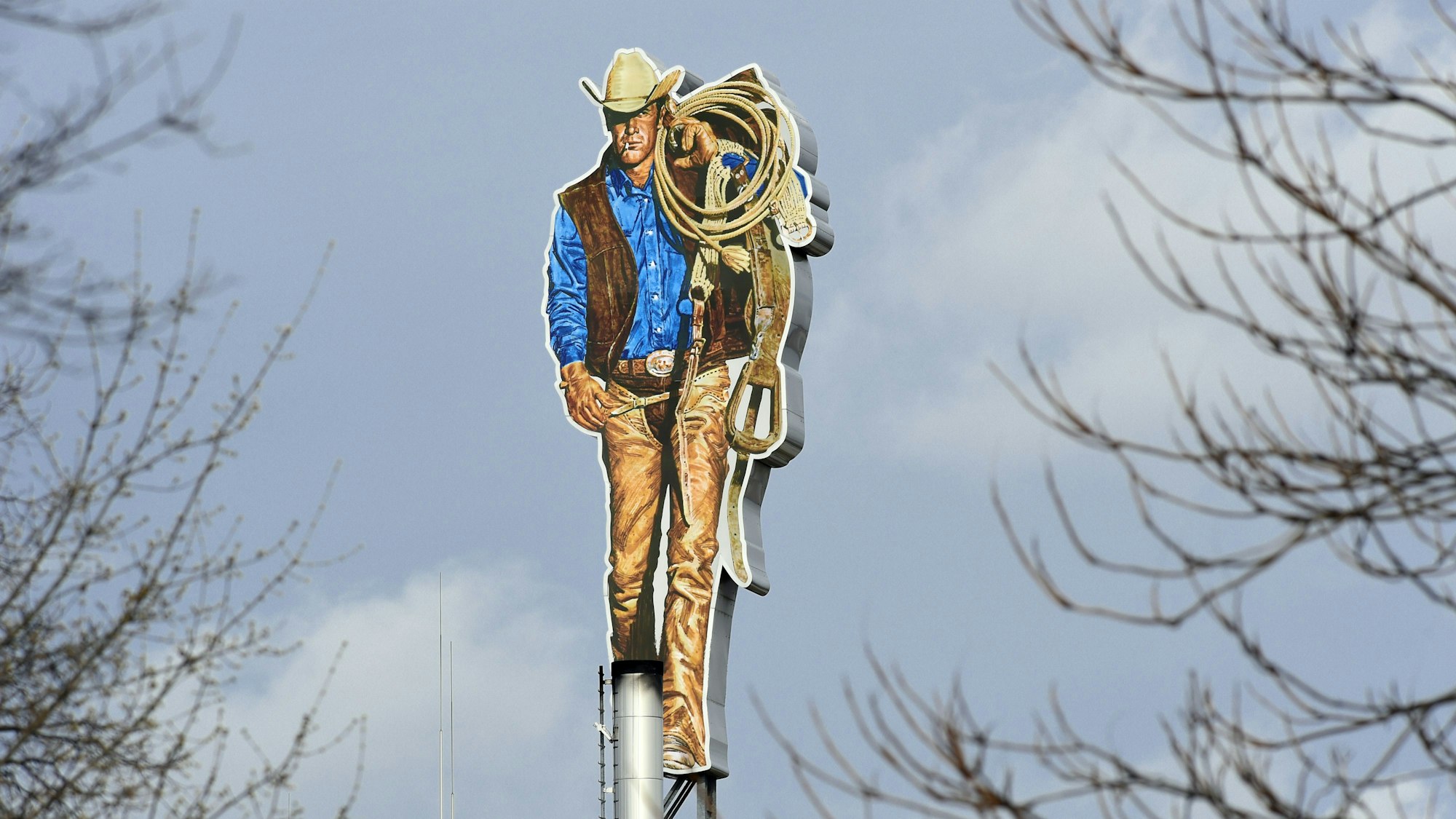 Der Marlboro Man steht in Berlin auf dem Dach der Zigarettenfabrik «Philip Morris» scheinbar zwischen den kahlen Ästen von Bäumen.