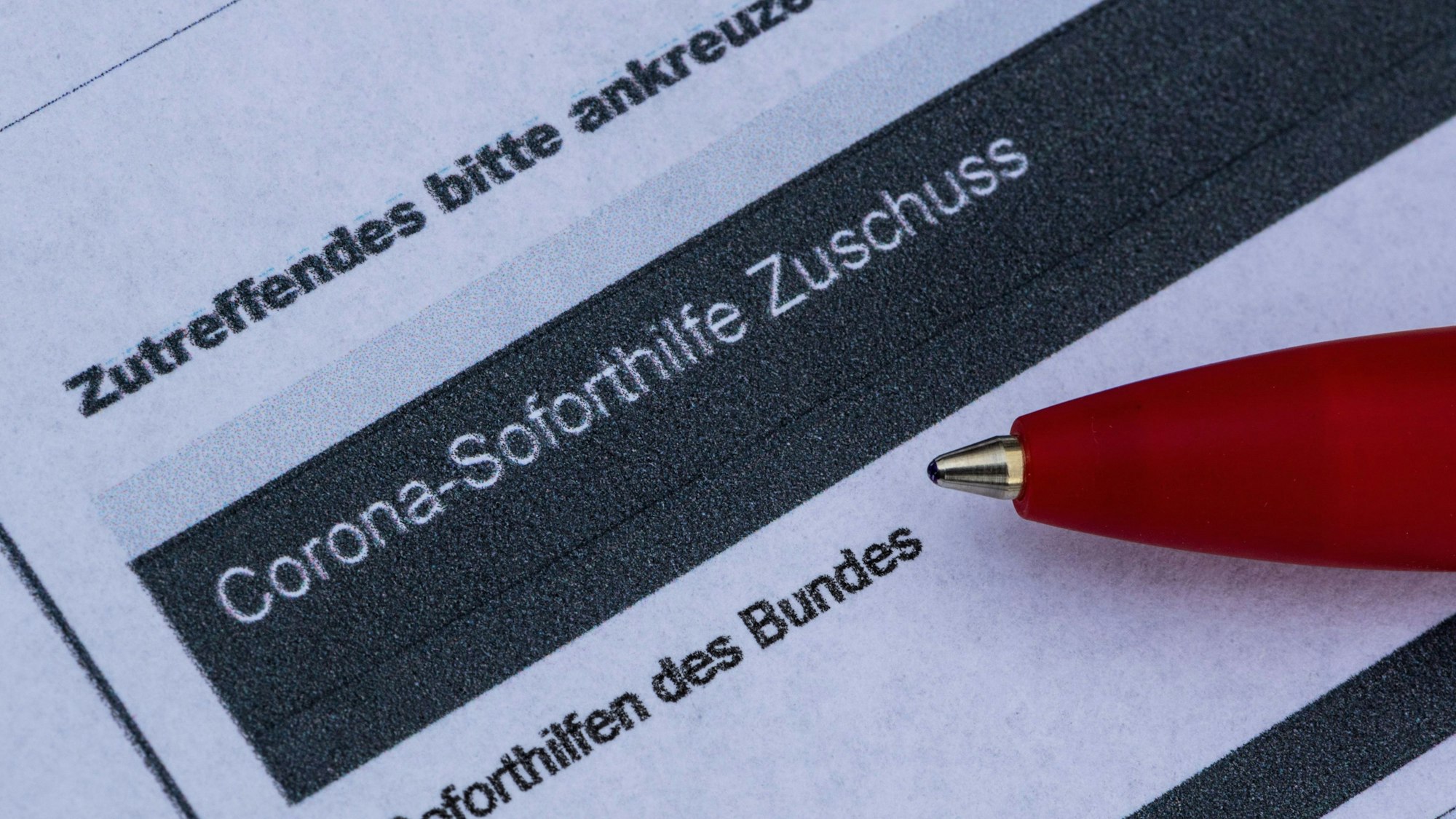 Ein Stift liegt auf einem Antrag für den Corona-Soforthilfe-Zuschuss.