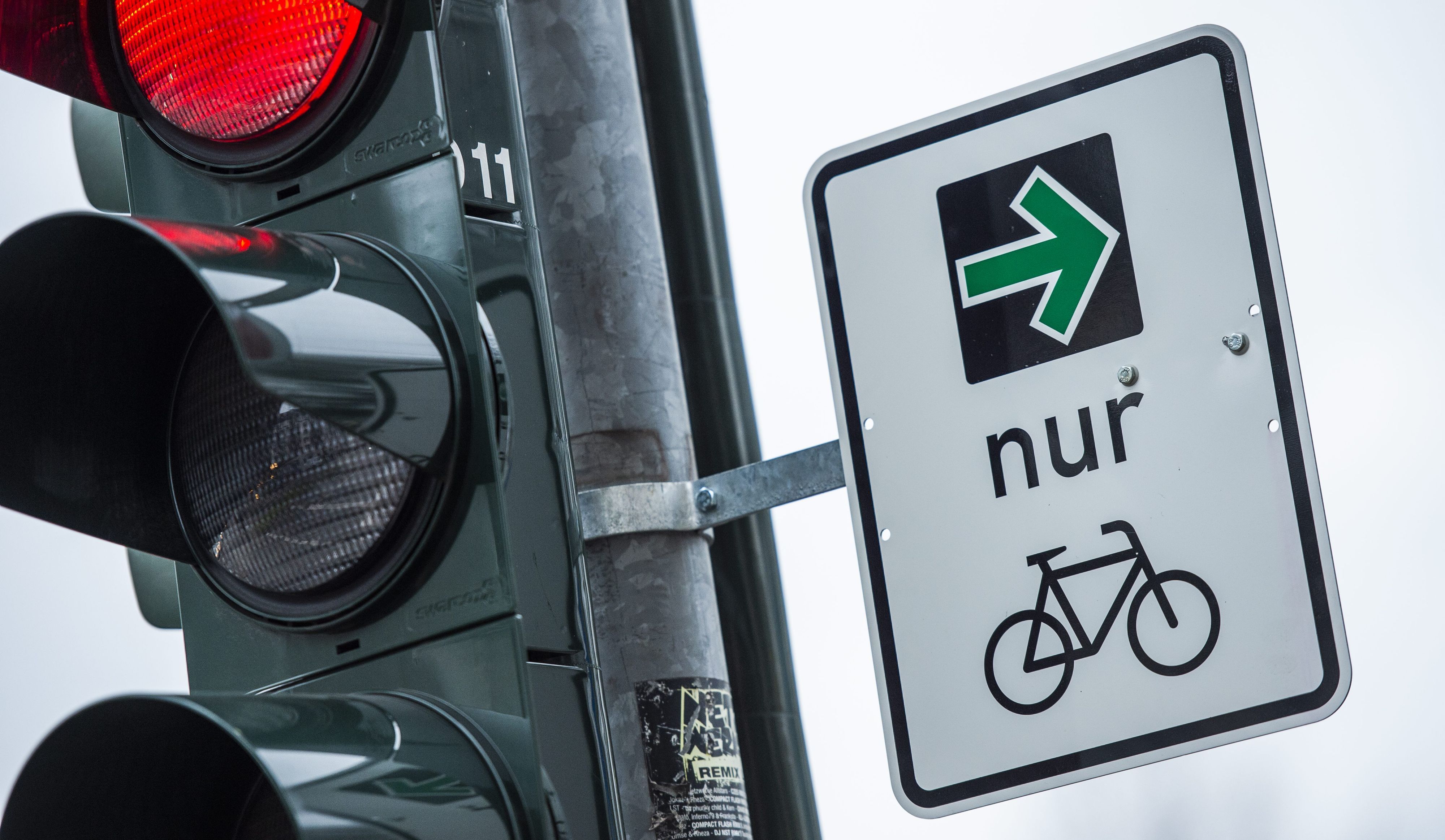 An einer Ampel einer Kreuzung hängt ein grüner Pfeil, der es Fahrradfahrern erlaubt rechts abzubiegen, wenn die Ampel rot ist.
