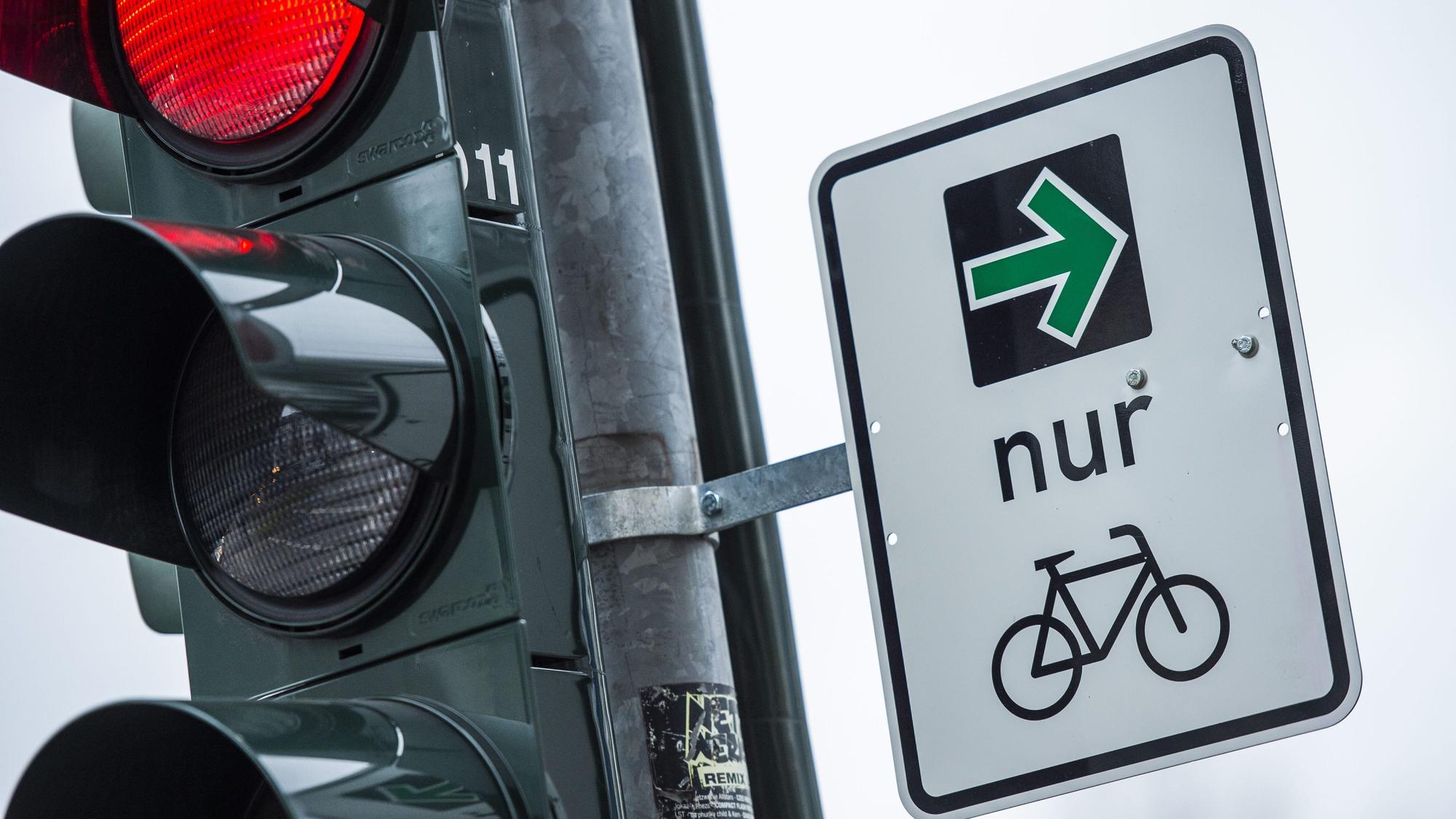An einer Ampel einer Kreuzung hängt ein grüner Pfeil, der es Fahrradfahrern erlaubt rechts abzubiegen, wenn die Ampel rot ist.
