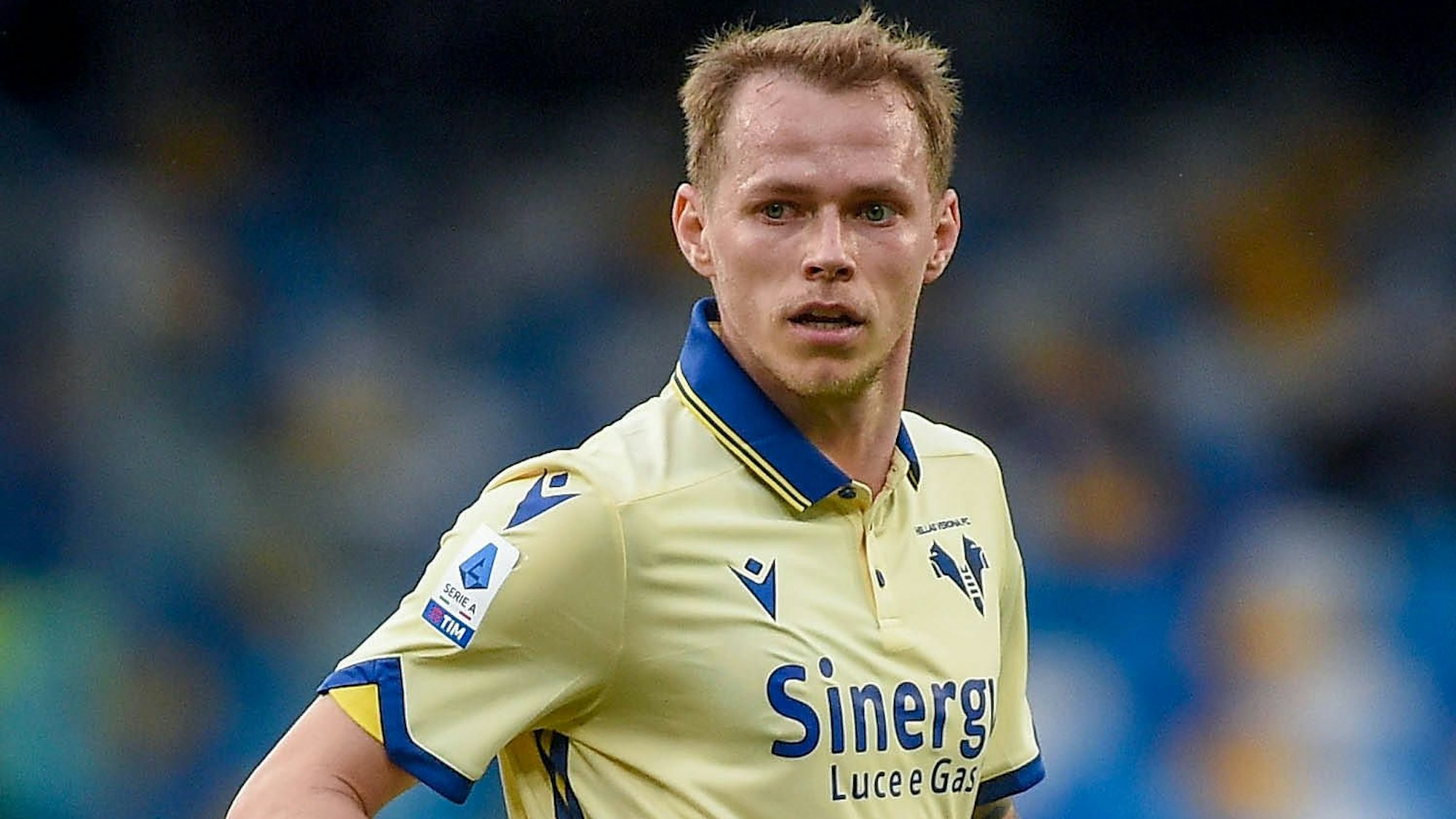Auf dem Bild schaut ein Fußballspieler mit verstrubbeltem Haar etwas glasig in die Ferne.