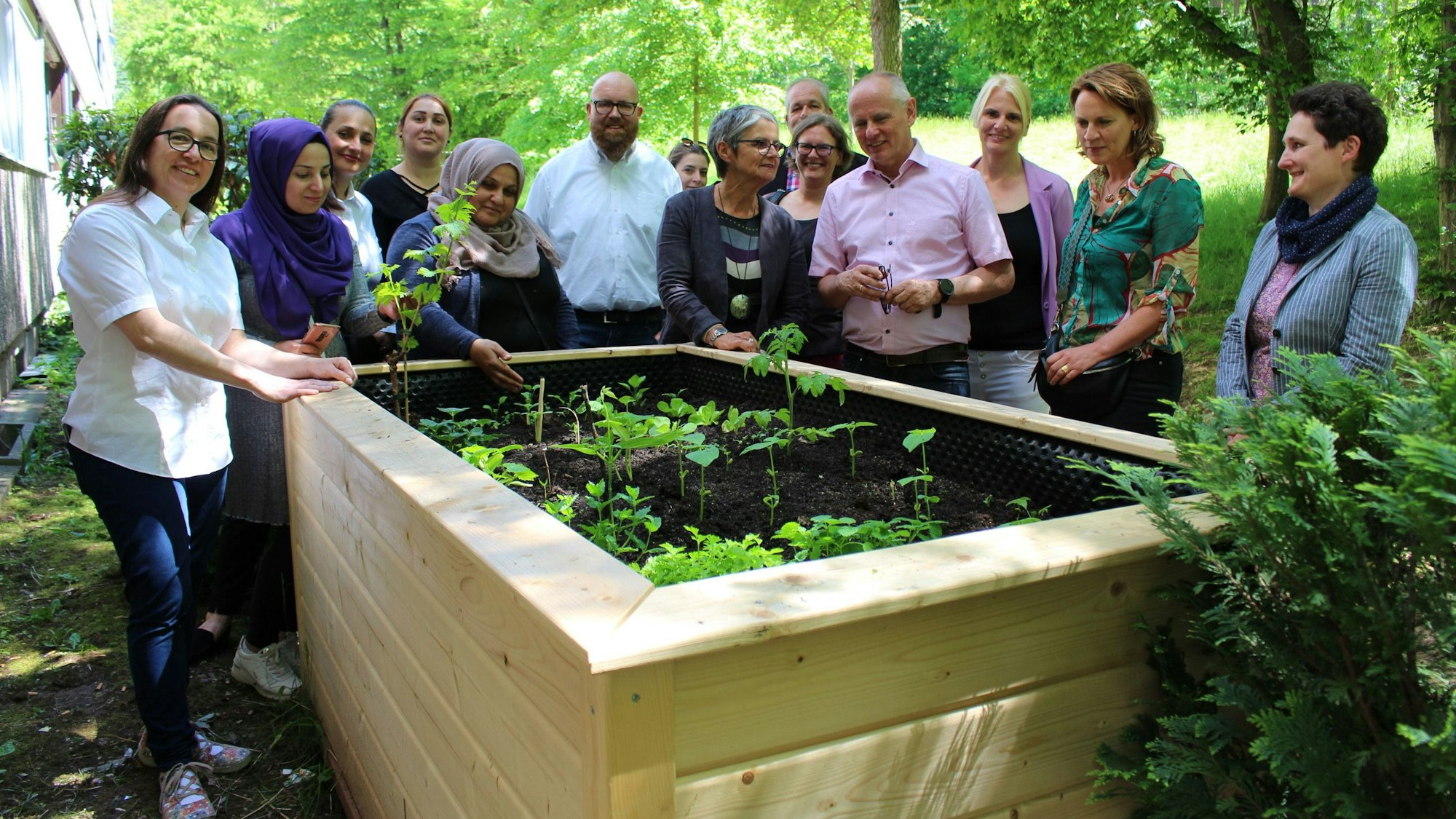 Die Teilnehmer des Projekts „Gesunde Quartiere“ haben sich um ein Hochbeet versammelt.