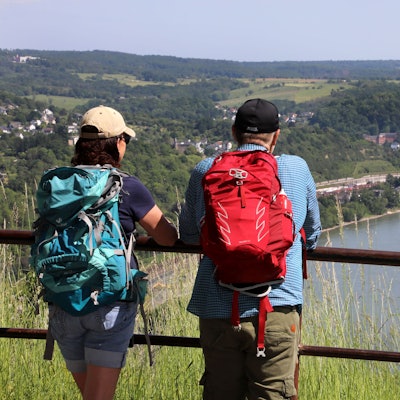 Zwei Wanderer schauen von einer Anhöhe auf den Rhein