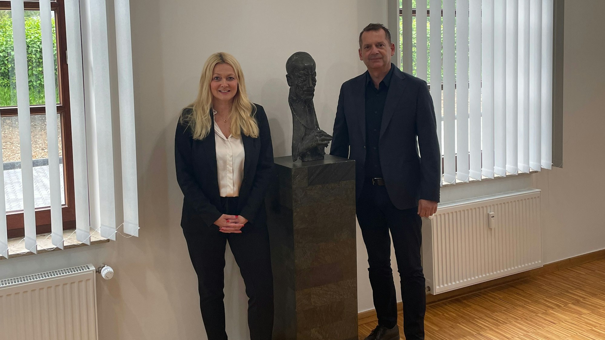 Es sind Helga und Michael Abels mit einem Exemplar der Bronzebüste von Kardinal Frings zu sehen.