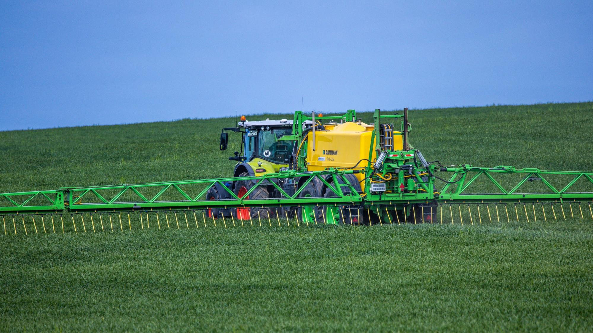 Ein Traktor verteilt Dünger auf einem Feld. In Dünger ist Nitrat enthalten, das bei zu intensivem Düngen gefährliche Rückstände im Grundwasser hinterlassen kann. Nun hat die EU-Kommission ein Verfahren um nitrathaltiges Wasser eingestellt. (Symbolbild)