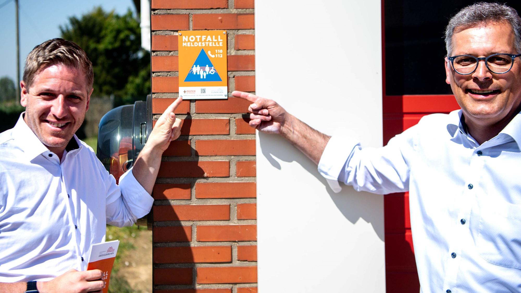 Der Kreis Euskirchen hat das Prinzip der Notfallmeldestellen vorgestellt. Zu erkennen sind die Anlaufstellen an den Plaketten. Landrat Markus Ramers und Zülpichs Bürgermeister Ulf Hürtgen am Feuerwehrgerätehaus in Juntersdorf.