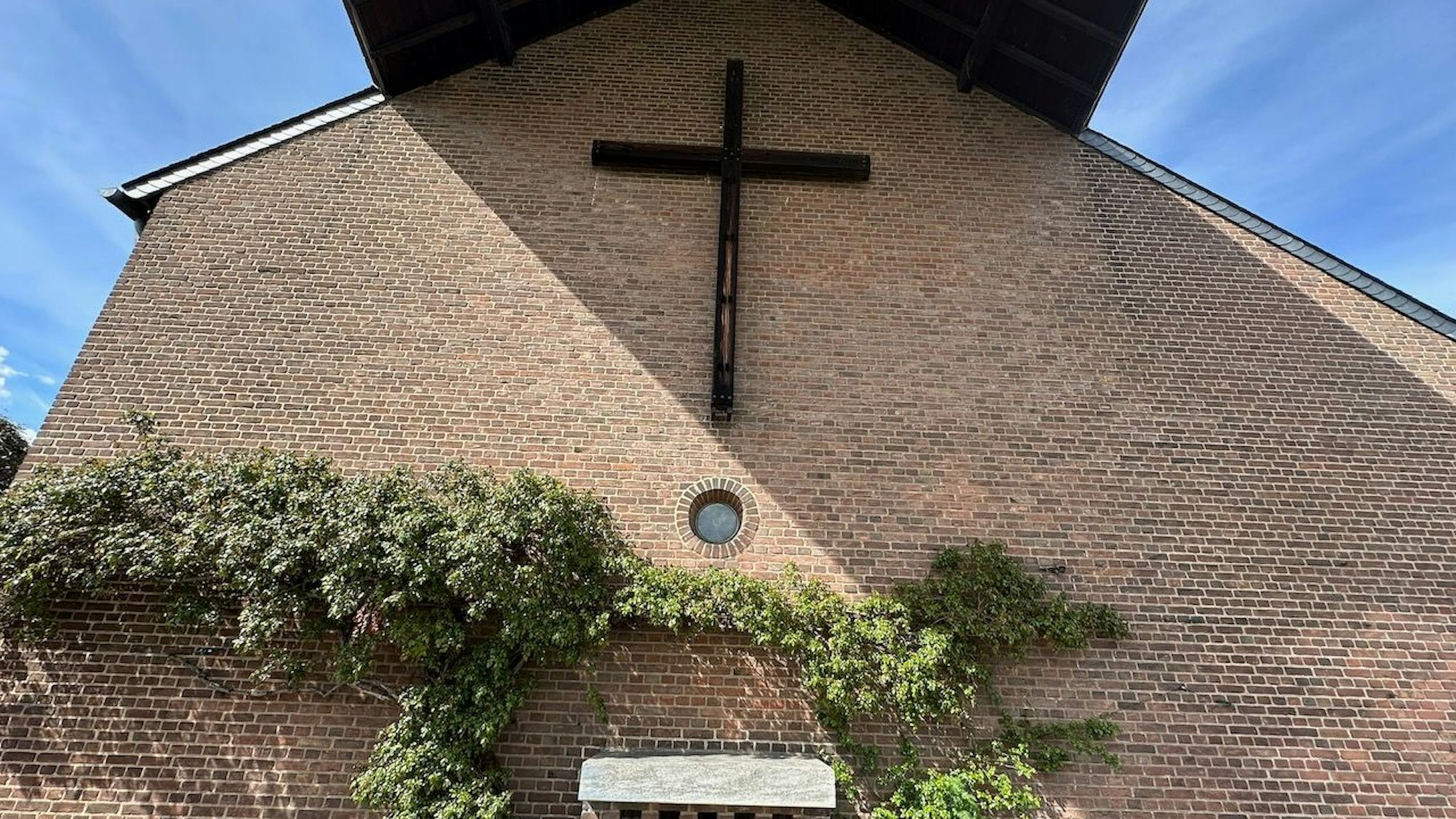 Die Pfarrkirche St. Georg hat einen Außenalter mit Rundfenster und Kreuz.