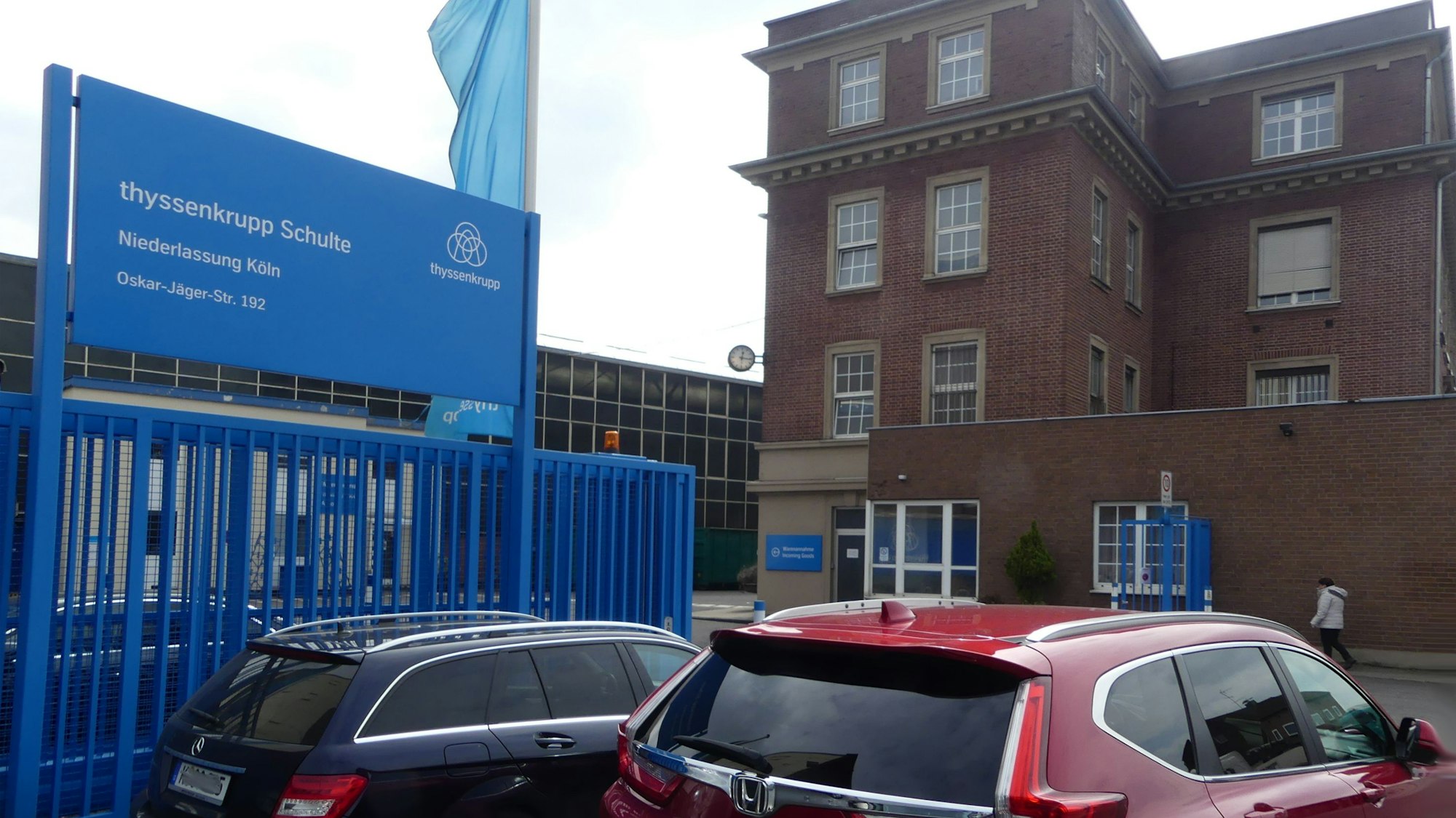 Vor dem Eingang zu einem Werksgelände parken zwei Autos. Auf einem Schild ist der Firmenname Thyssenkrupp Schulte zu lesen.