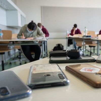 Ausgeschaltete Smartphones liegen in einem Klassenzimmer.