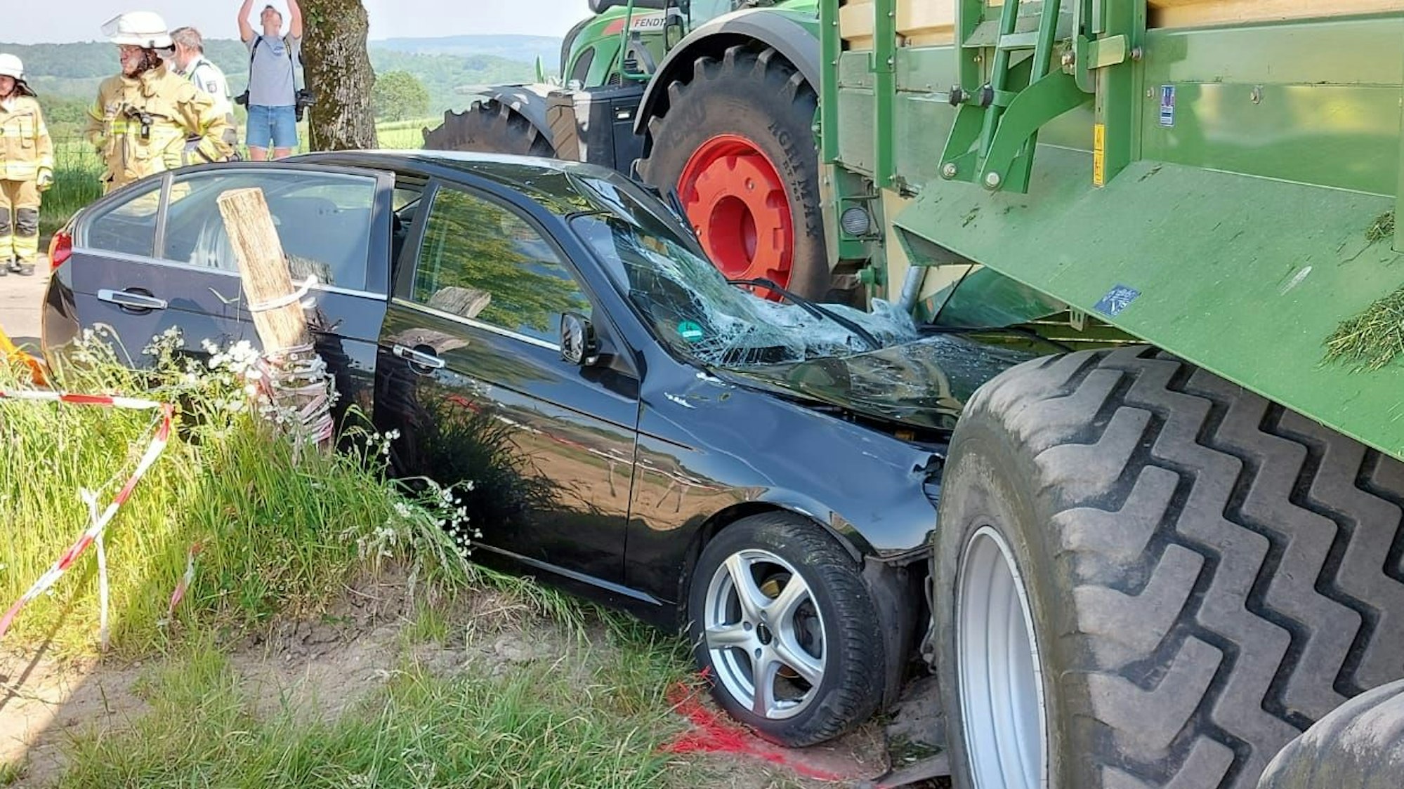 Feuerwehrleute und Polizisten stehen um das Wrack herum.