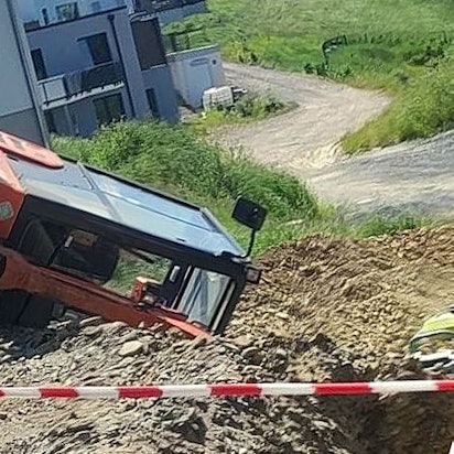 Ein Bagger liegt an einem Abhang auf der Seite, im Vordergrund ist Absperrband gespannt.
