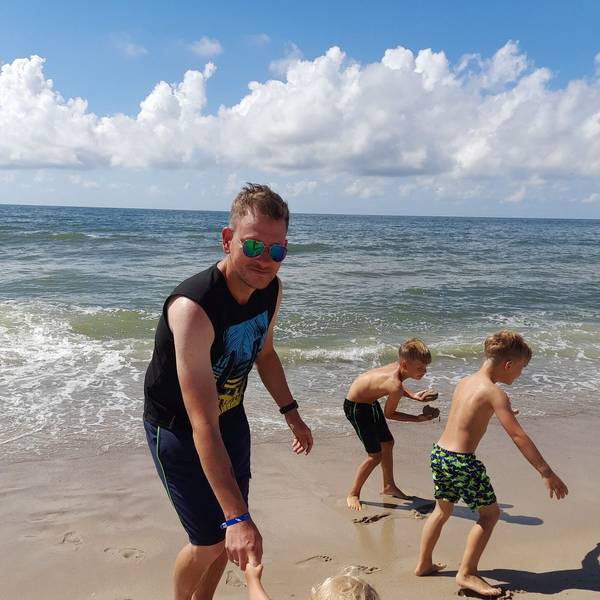 Ein Mann spielt am Strand mit seinen Kindern.