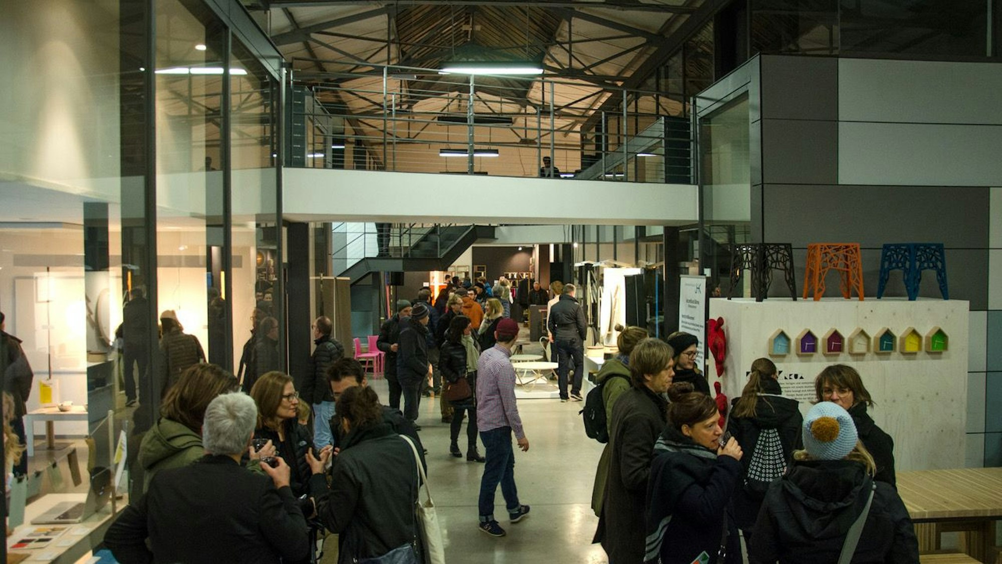 Besucher stehen in einer Halle und gucken sich Ausstellungsstücke an.