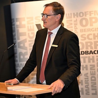 Ein Mann in Anzug und Krawatte steht an einem Rednerpult.