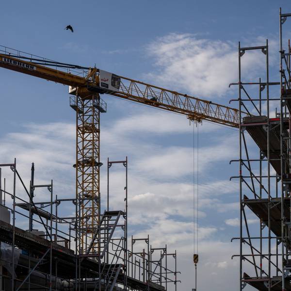Ein Turmdrehkran ragt in den Himmel auf einer Baustelle zwischen neu errichteten Wohnhäusern. Der Wohnungsbau in Köln stagniert seit Jahren auf niedrigem Niveau. (Symbolbild)