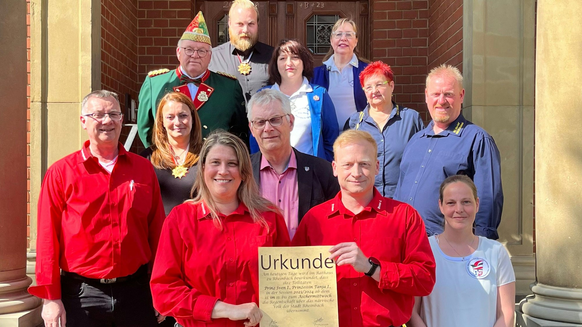 Auf Stufen präsentiert das Rheinbacher Prinzenpaar eine Urkunde.