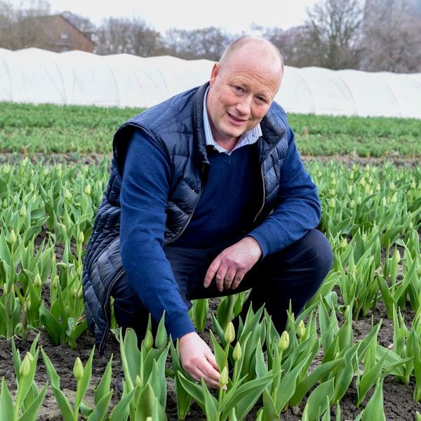 Peter Zens kniet in einem Blumenfeld.