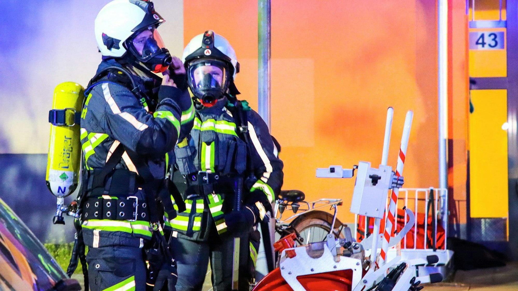 Feuerwehrleute legen ihren Atemschutz zur Bekämpfung eines Kellerbrandes in einem Wohnblock an.