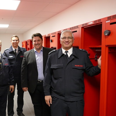 Zu sehen sind Löschgruppenführer Ralf Eich, Leiter der Troisdorfer Feuerwehr, Lars Gödel, Bürgermeister Alexander Biber und Löschgruppenführer Salvatore Rizzello zwischen roten Schränken.