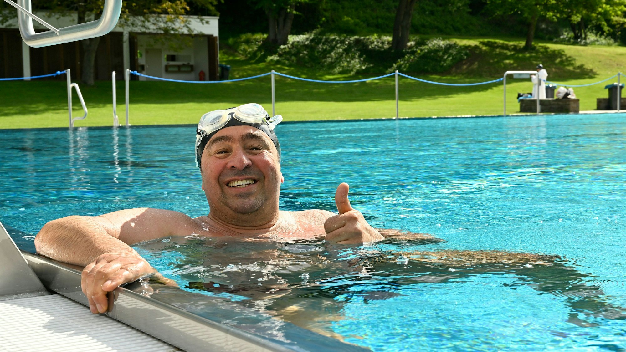 Ein Mann hält sich am Beckenrand des Schwimmeckens fest.