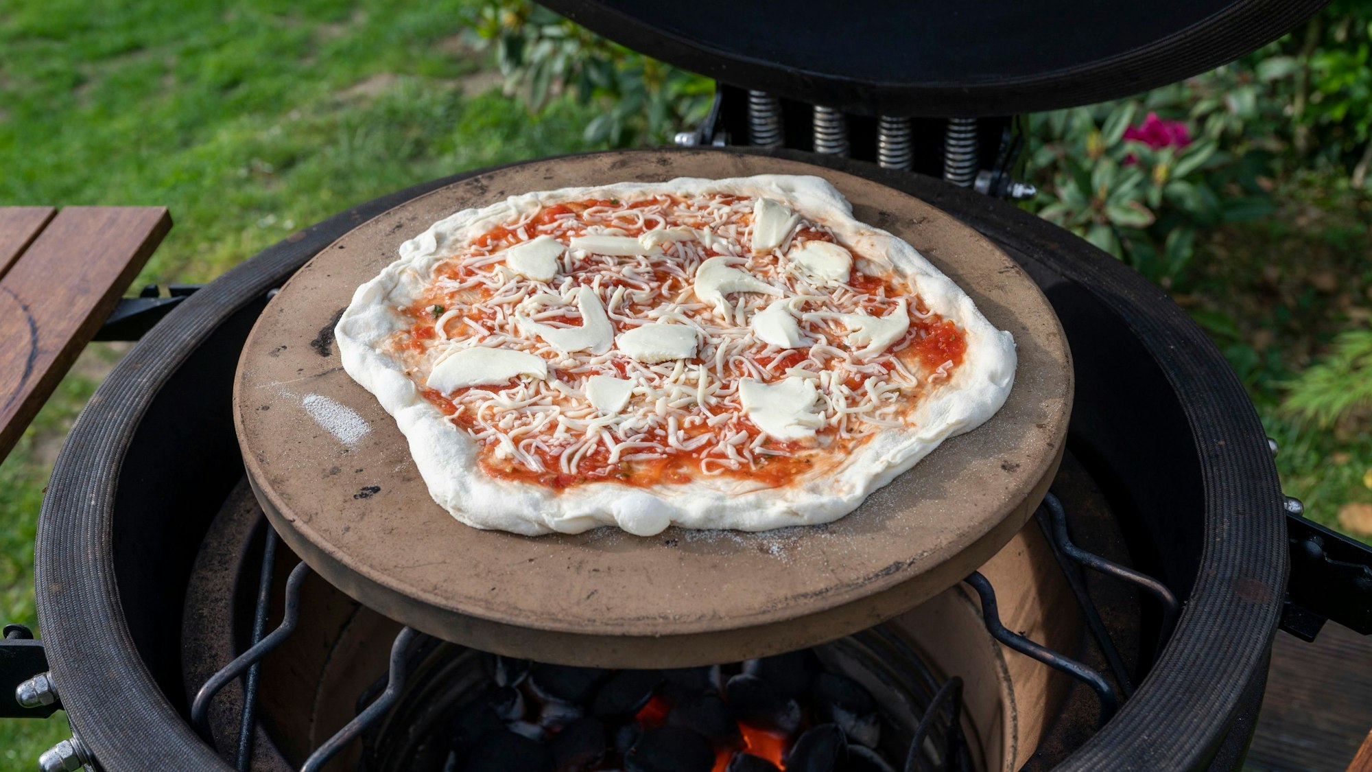 Eine Pizza liegt auf einem Grill.