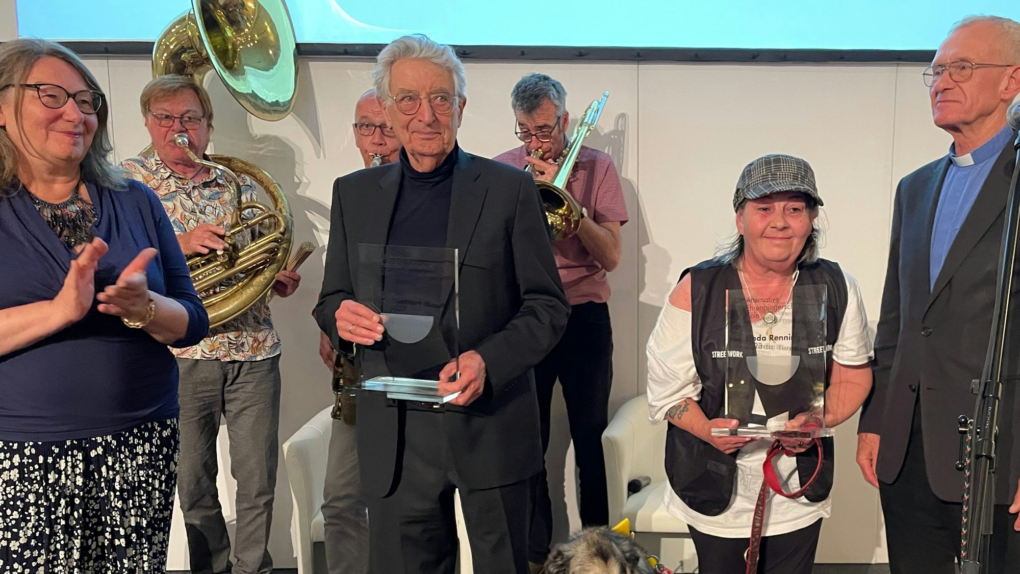 Für ihren Kampf um Menschenrechte geehrt wurden Gerhart Baum und Linda Rennings (2. und 3. v. links). Überreicht wurden die Preise von Irene Franken, Mitgründerin des Frauengeschichtsvereins (l.) und Pfarrer Franz Meurer. Beide wurden in den Vorjahren mit der "Alternativen Kölner Ehrenbürgerschaft" ausgezeichnet. Alle vier stehen nebeneinander auf dem Podium und freuen sich.