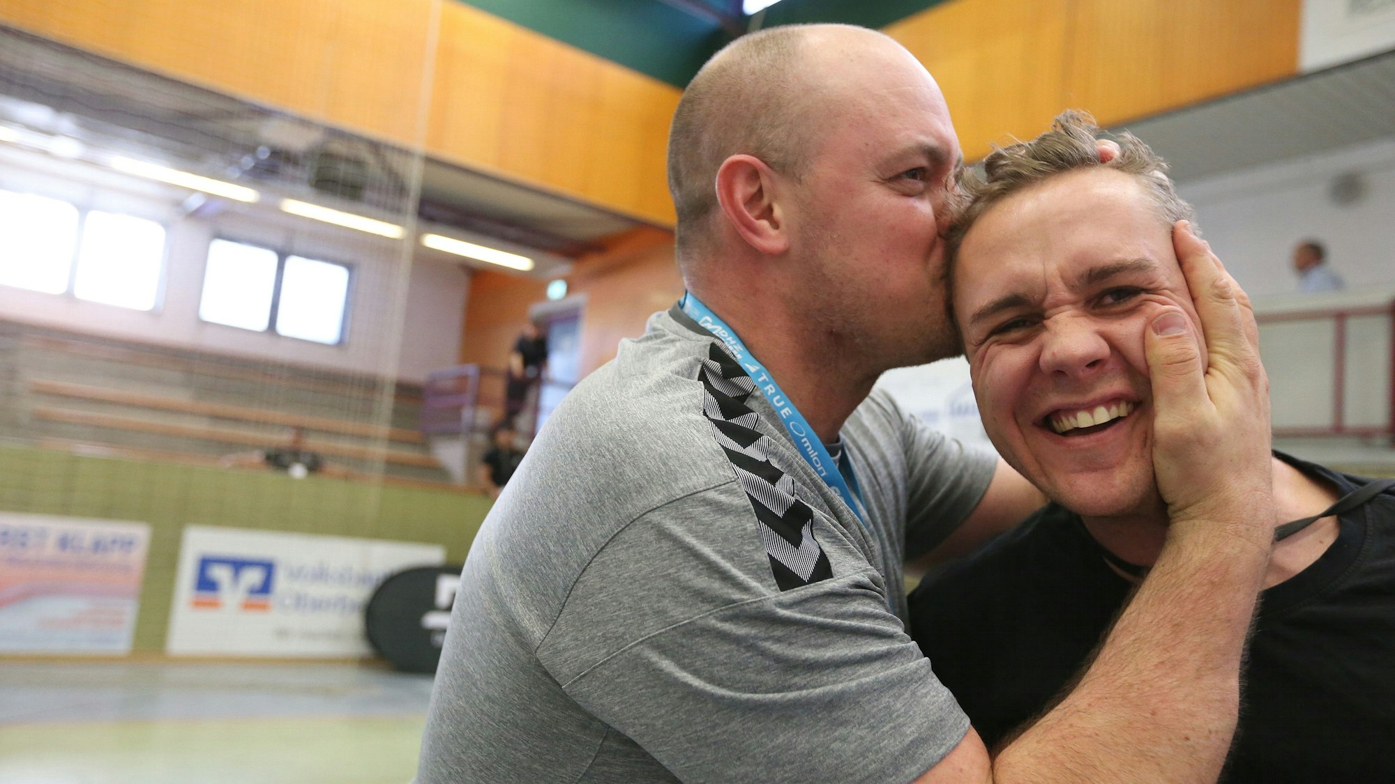 Ein Mann küsst einen anderen Mann auf den Kopf.