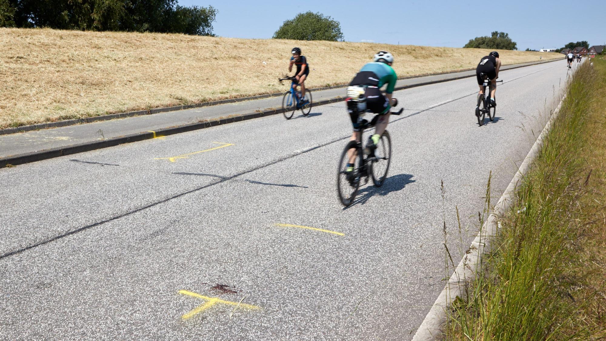 Tragödie in Hamburg: Teilnehmer der Ironman-EM fahren auf der Straße des Unfallorts, wo ein Motorradfahrer tödlich verunglückte.