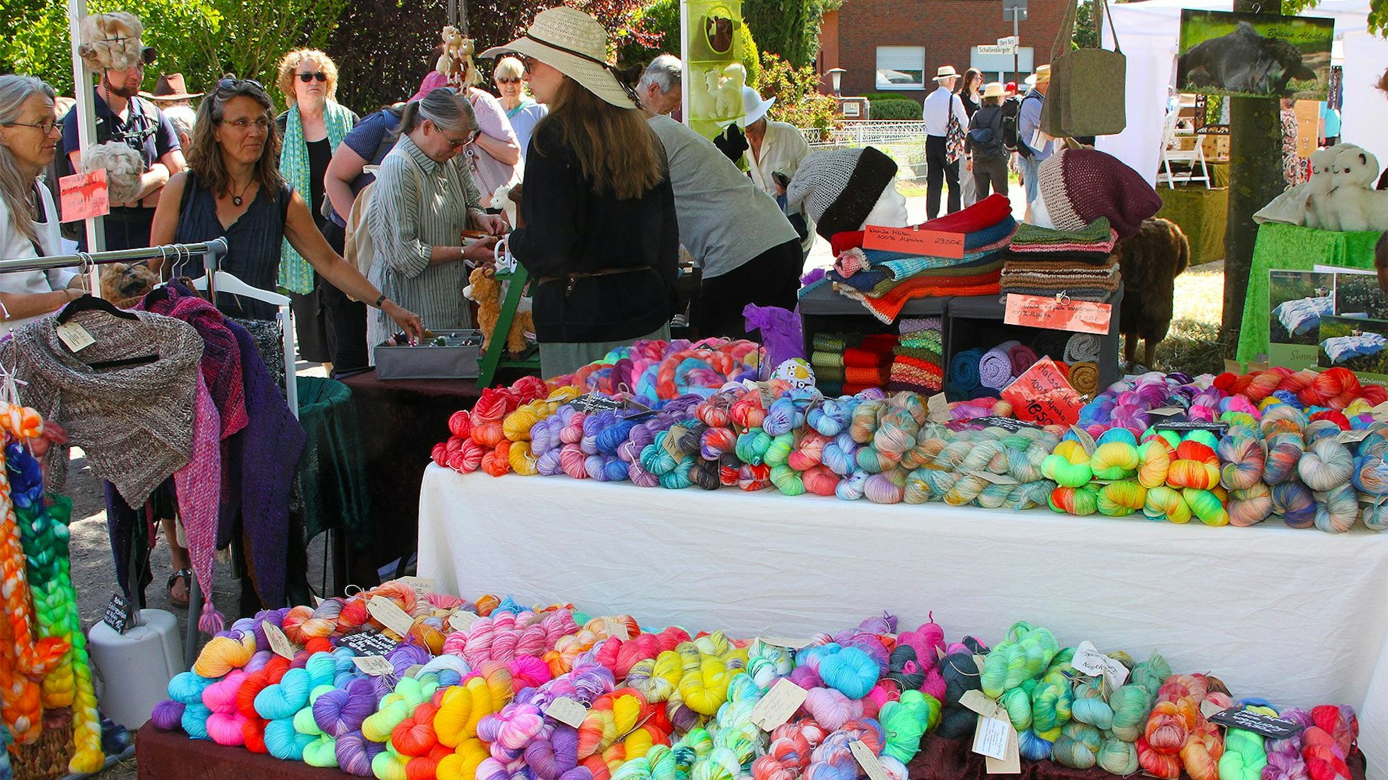 Das Bild zeigt einen Marktstand, auf dem zahlreiche bunte Wollknäuel präsentiert werden.