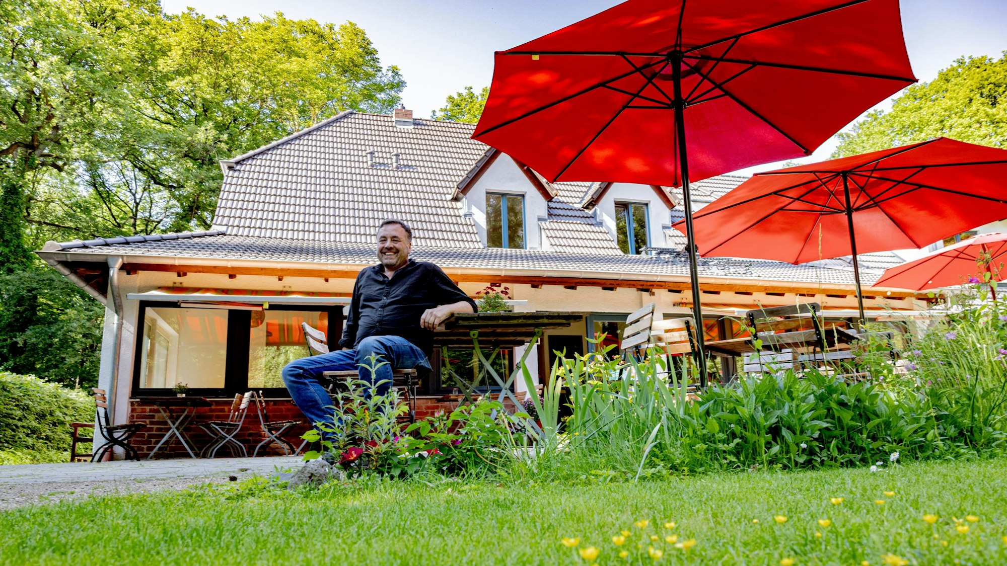 Eric von Bülow lädt in die Waldschenke ein, wo alte Bäume und Schirme Schatten verheißen.