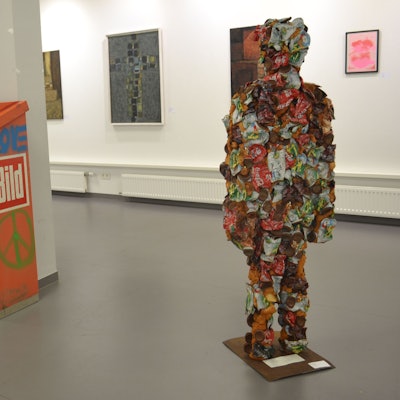 Eine Figur aus Müll steht inmitten einer Ausstellung.