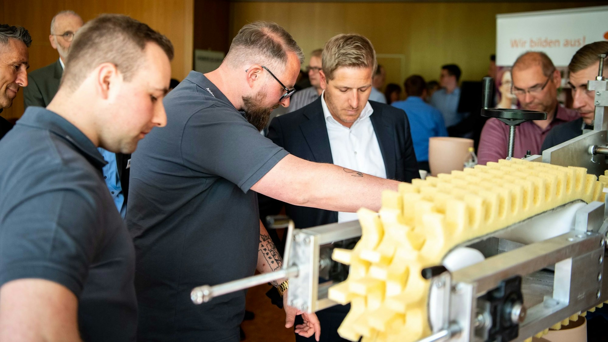 Das Bild zeigt eine Gruppe Menschen, die eine neue Maschine anschauen.