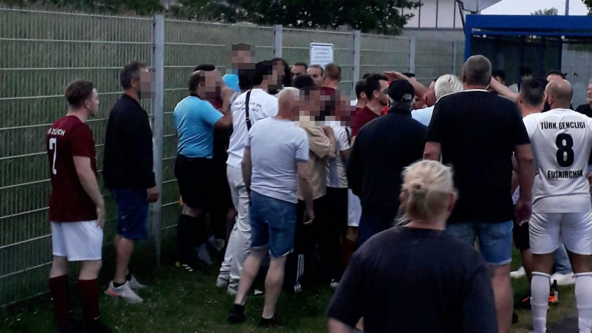 Ein Schiedsrichter und sein Assistent mit einem Pulk aufgebrachter Zuschauer.