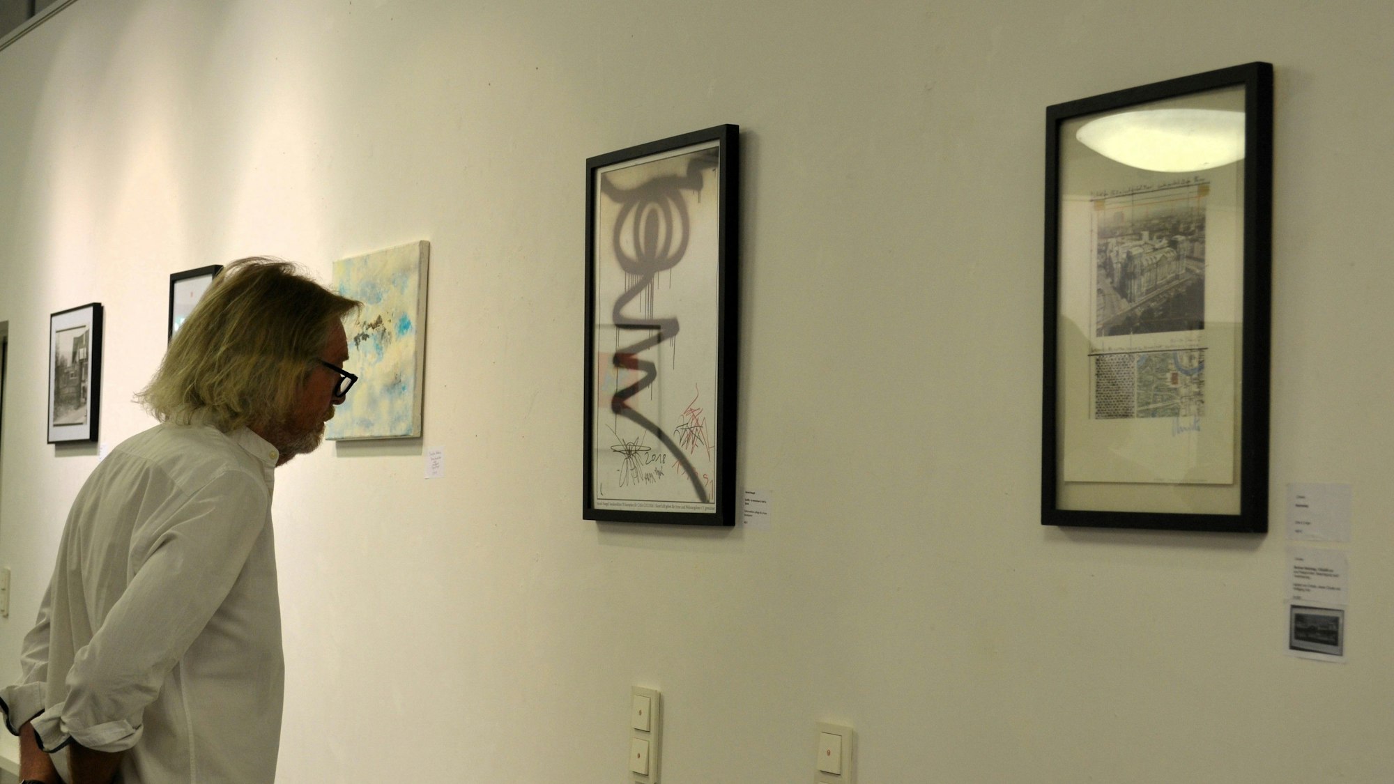 Ein Mann schaut sich Bilder bei einer Ausstellung an.