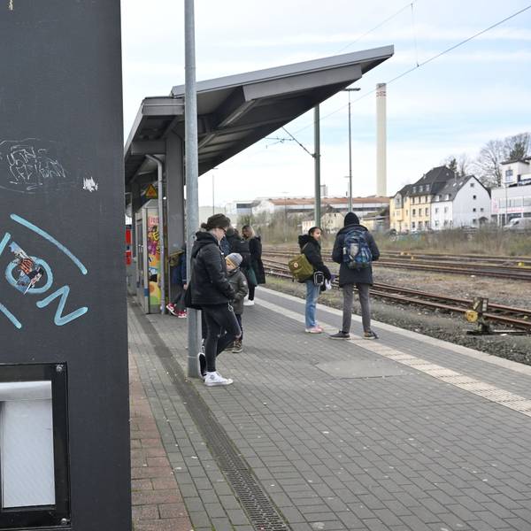 Menschen stehen am Bahnhof.