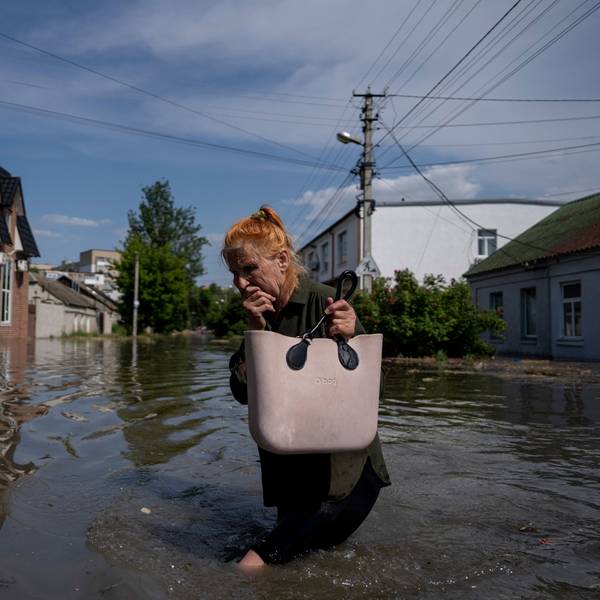 6. Juni 2023, Ukraine, Cherson: Eine Anwohnerin bahnt sich einen Weg durch eine überflutete Straße.